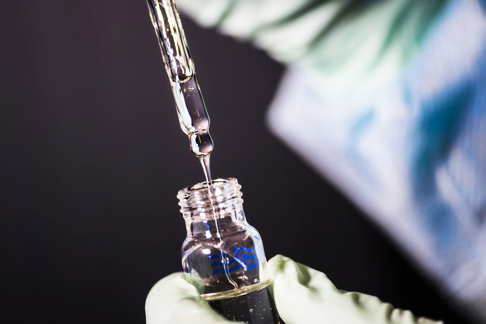 Pipette dripping liquid into a glass vial